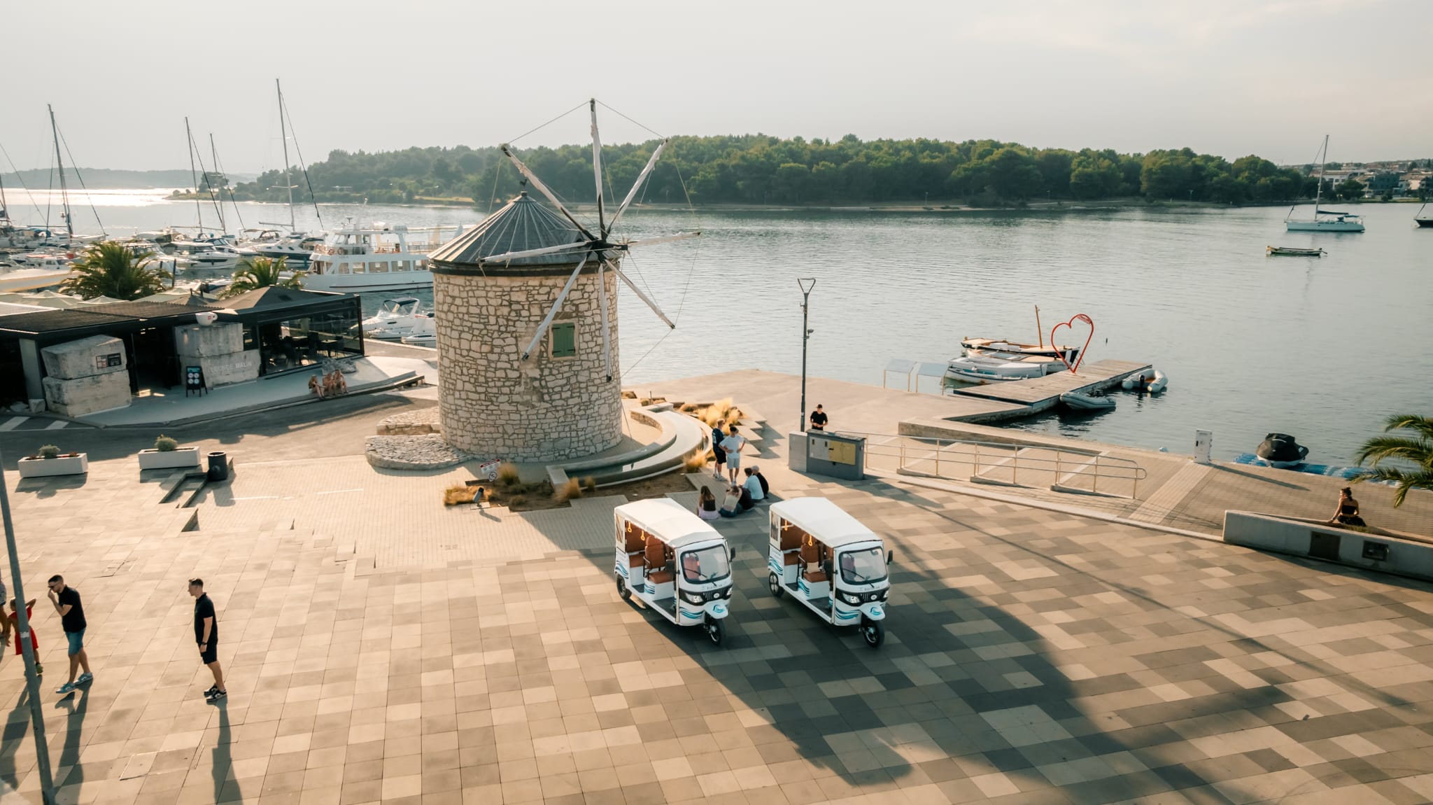 Drone view of both tuk-tuks by the old windmill on the Medulin riva and harbor