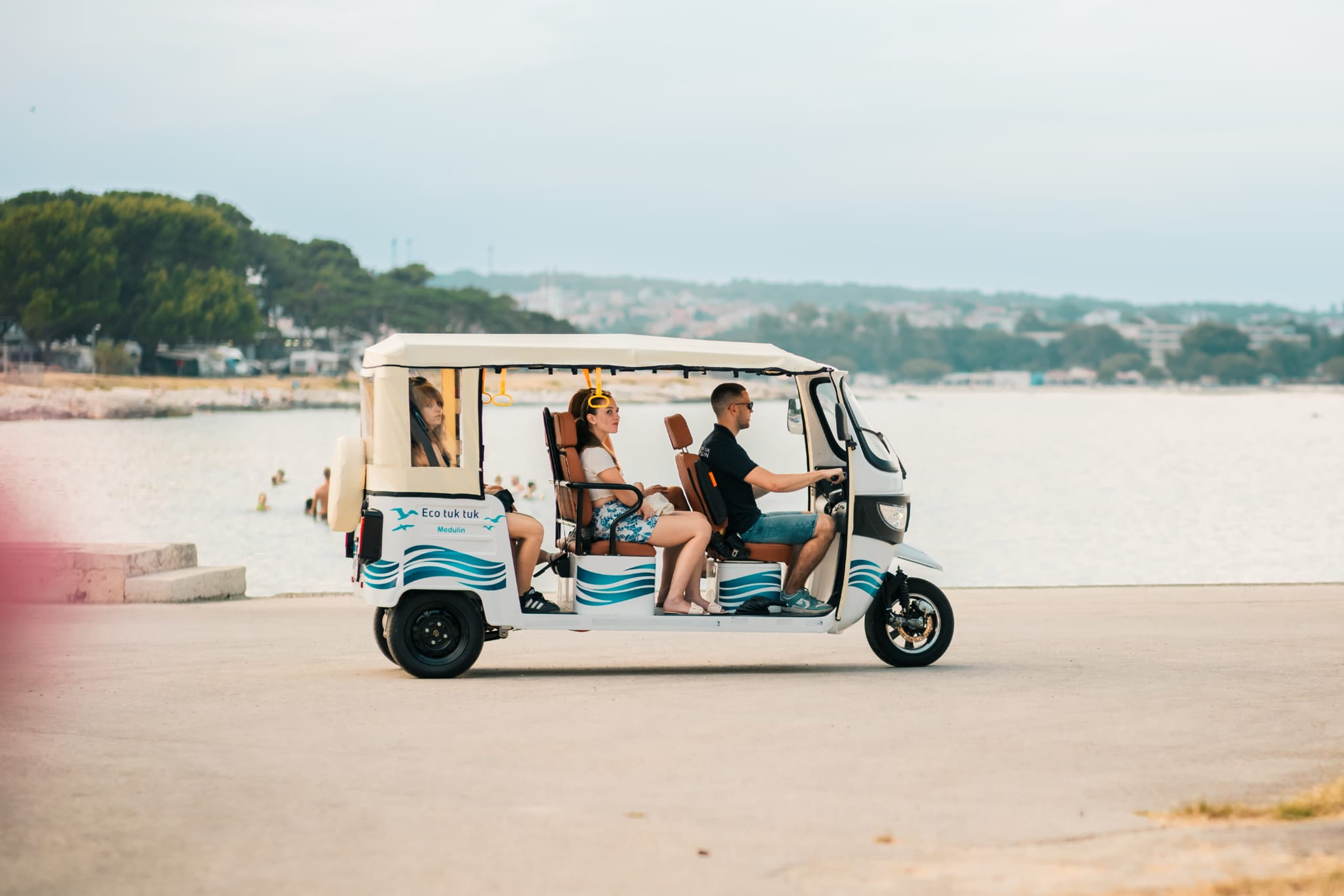 Tuk-tuk driving along the seafront at Bijeca beach in Medulin